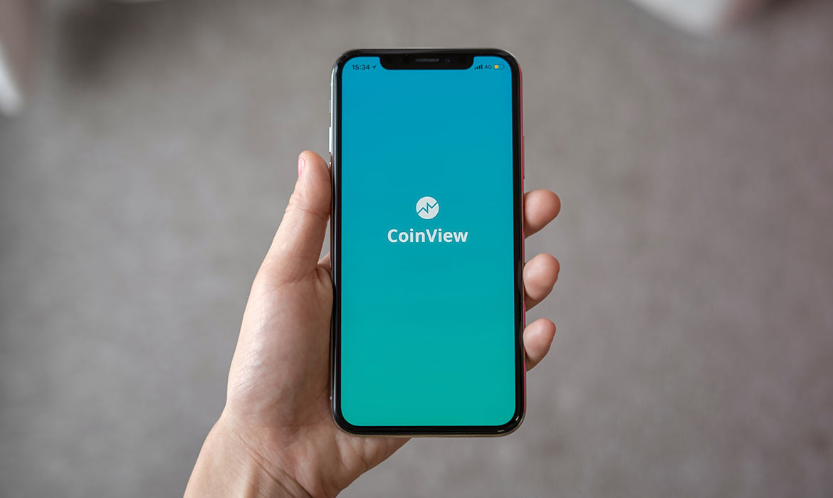 Hand holding smartphone with CoinView app screen