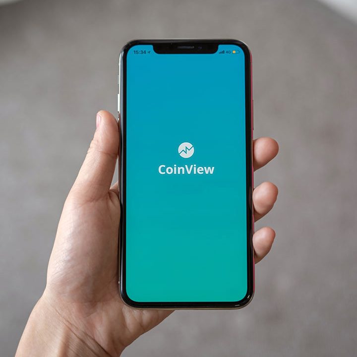 Hand holding smartphone displaying CoinView app