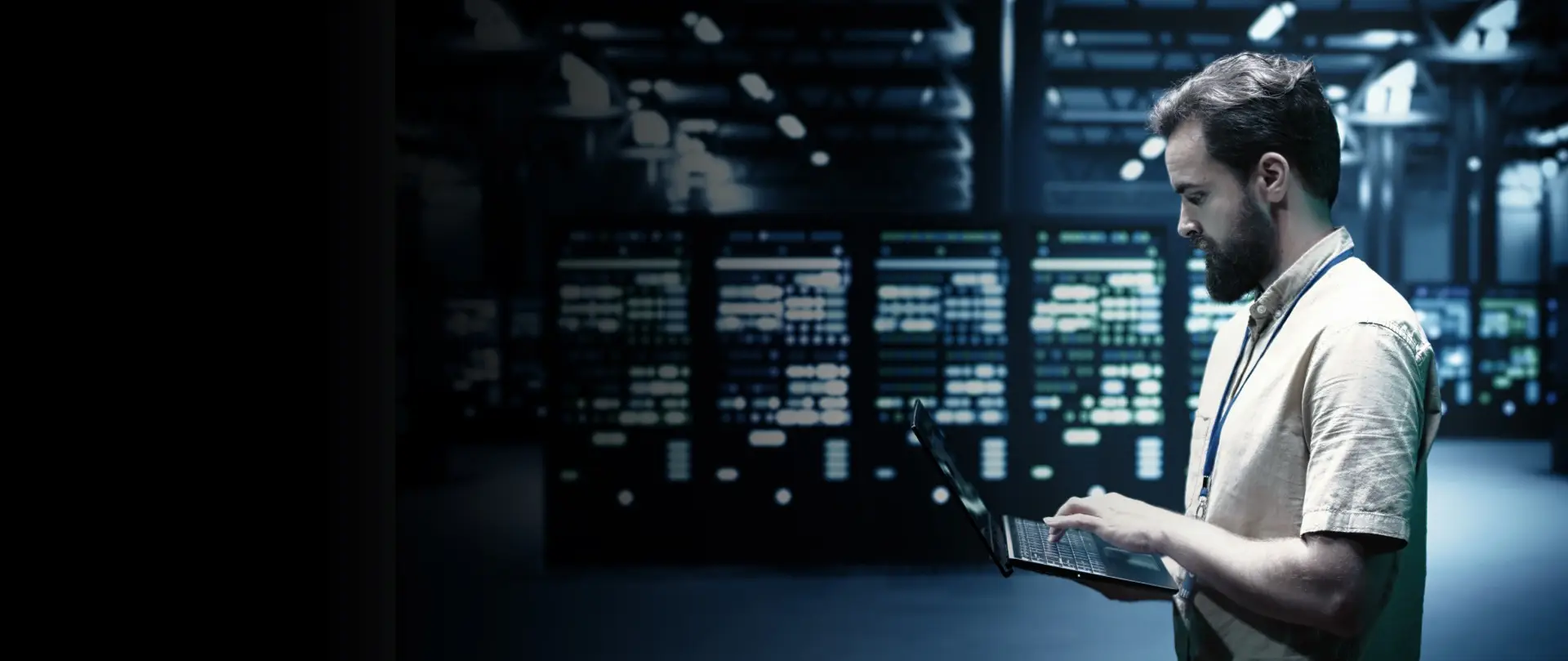 IT specialist using a laptop while monitoring systems inside a secure data center