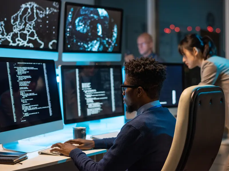 Cybersecurity analysts monitoring systems on multiple screens
